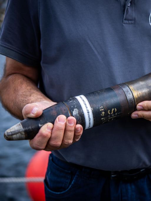 Ein Mitarbeiter des Munitionsbergungsdienst Mecklenburg-Vorpommern zeigt eine 7,5 Zentimeter Panzersprenggranatpatrone. Munition dieser Bauart wird bei der Pilotierungs-Bergung im Rahmen des Sofortprogramms „Munition im Meer“ in der Ostsee  gesichert. 