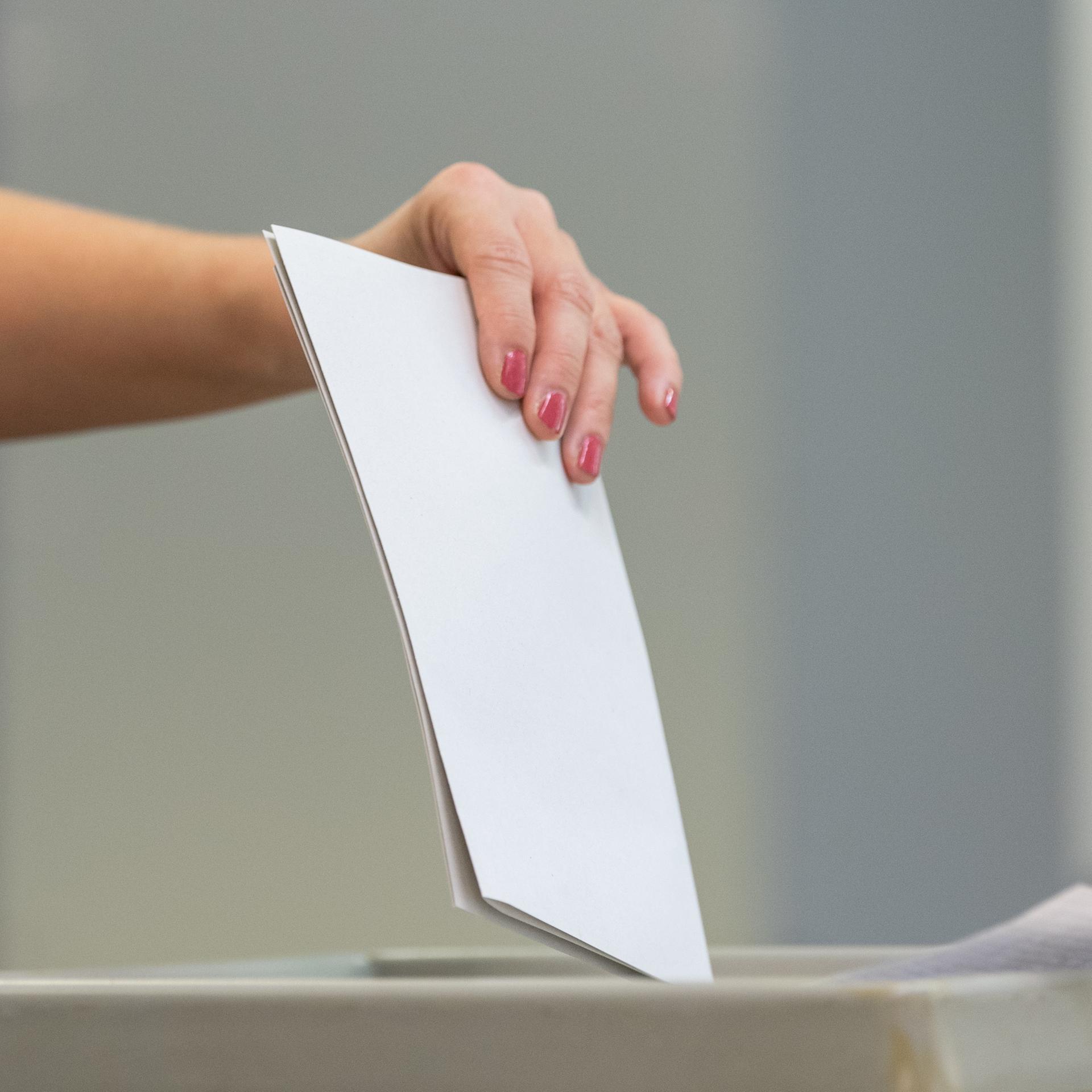 Eine Wählerin wirft bei der Stimmabgabe zur Landtagswahl in Sachsen den Wahlzettel in einem Wahllokal in eine Wahlurne.