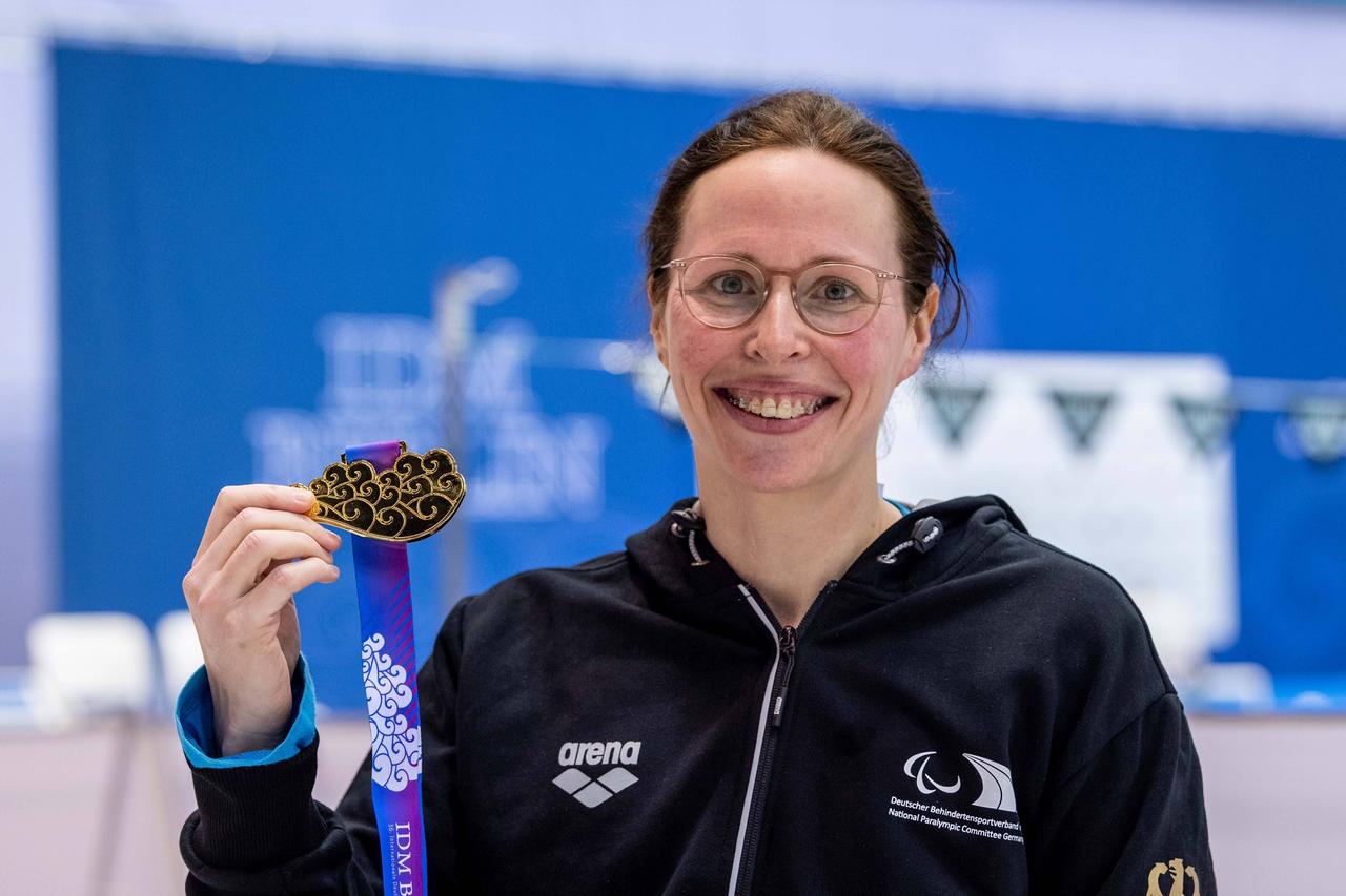 Tanja Scholz lächelt und zeigt ihre Medaille