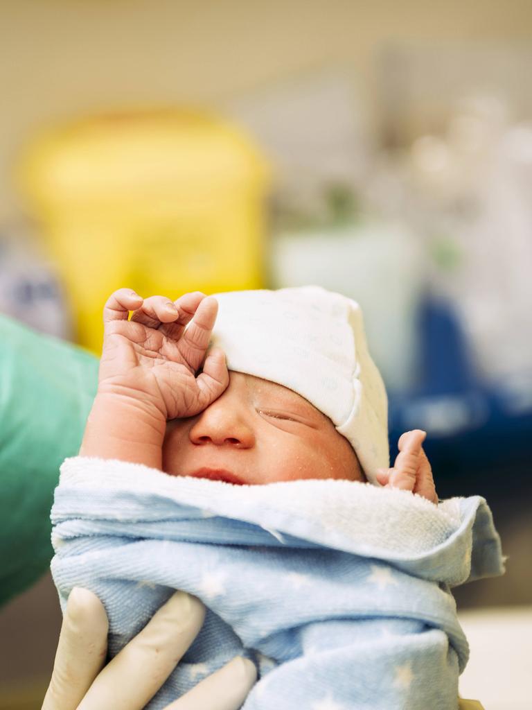 Ein neugeborenes Baby, eingewickelt in ein Handtuch, gehalten von einer Ärztin im Kreißsaal. Ein neugeborenes Baby, eingewickelt in ein Handtuch, gehalten von einer Ärztin im Kreißsaal.