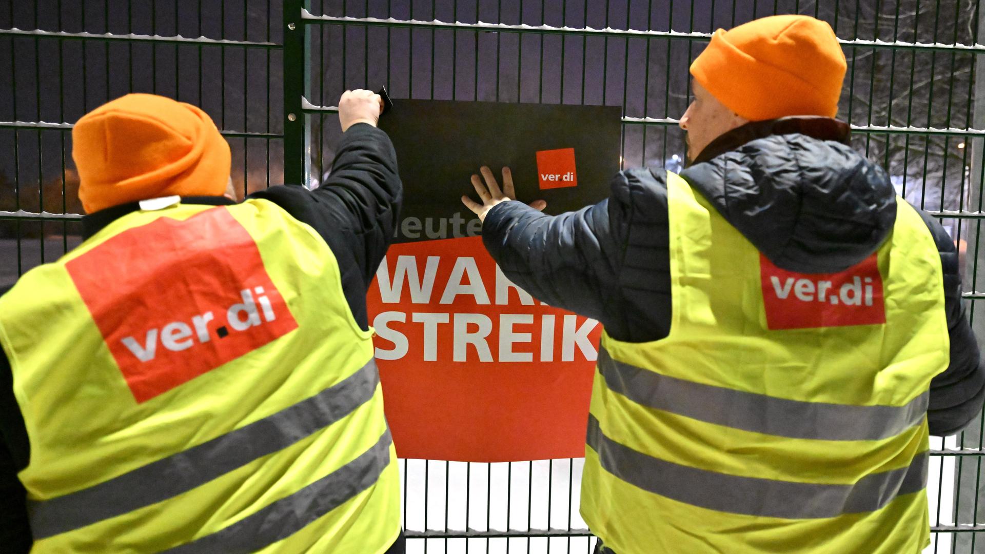 Gewerkschaftsmitglieder aus Thüringen bringen am Betriebshof der Erfurter Verkehrsbetriebe AG ein Plakat mit der Aufschrift "Warnstreik" an. 