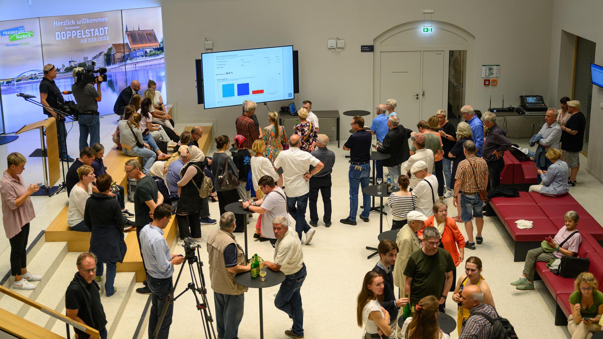 Zahreiche Menschen haben sich in der Rathaushalle von Frankfurt (Oder). Sie verfolgen das Auszählen der Stimmzettel zur Wahl des Oberbürgermeisters. 
