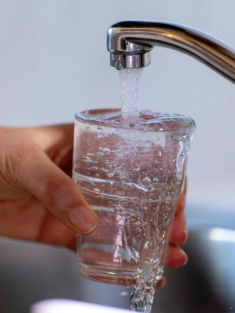 Eine Hand hält ein Glas unter einem Wasserhahn. 