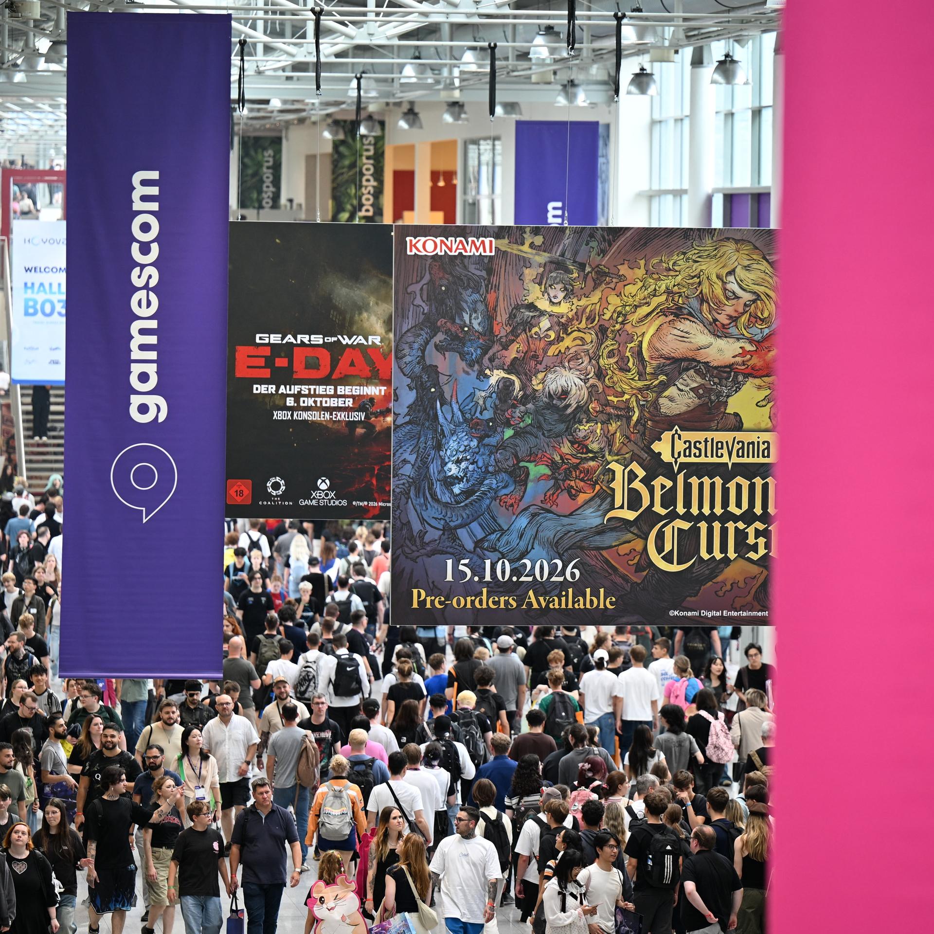 Besucher gehen am zweiten Tag der diesjährigen Computer- und Videospiel-Messe Gamescom durch einen Flur, von der Decke hängen Gamescom-Logos herab.