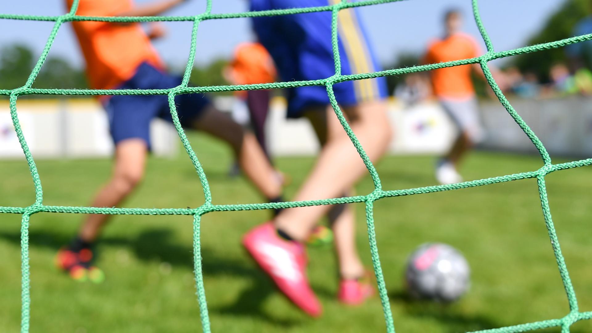 Kinder spielen auf einem Sportplatz Fußball.