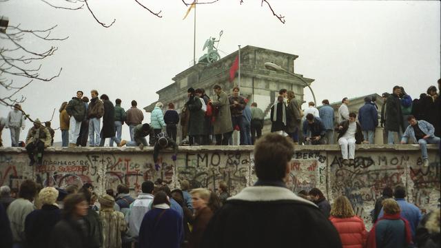 Menschen stehen vor und auf der Mauer am Brandenburger Tor nach der Wende vom 9. November 1989.