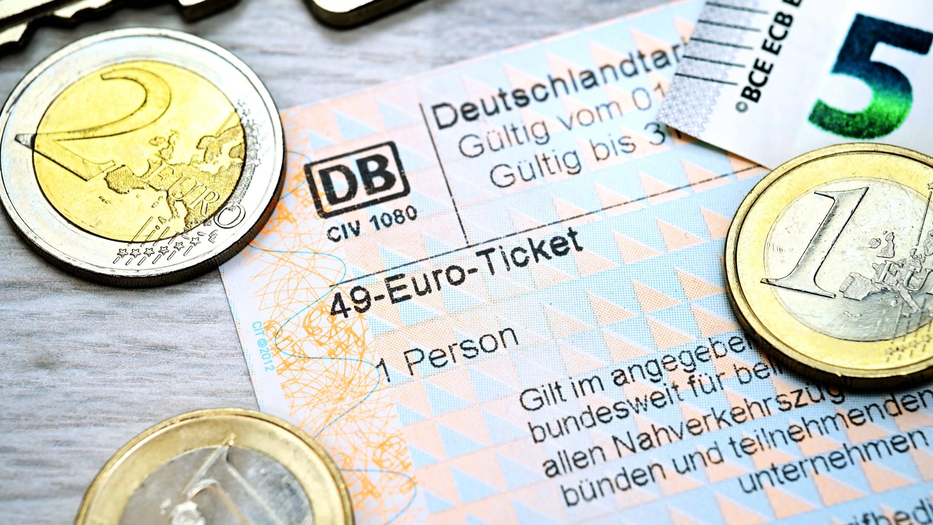 Fahrschein mit Aufschrift 49-Euro-Ticket und Euromünzen.