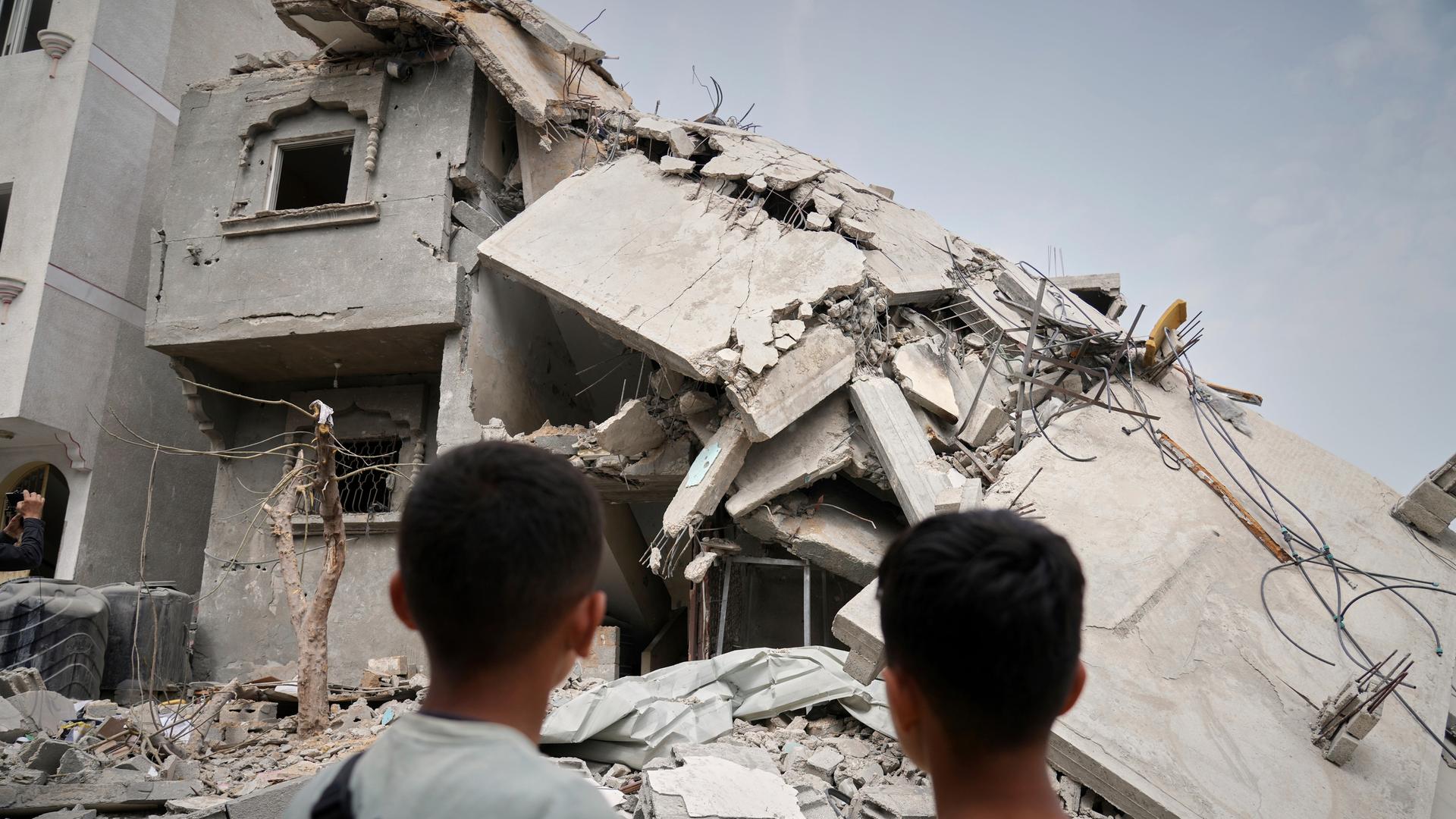 Kinder blicken nach einem israelischen Angriff auf den Gazastreifen auf ein zerstörtes Haus.
