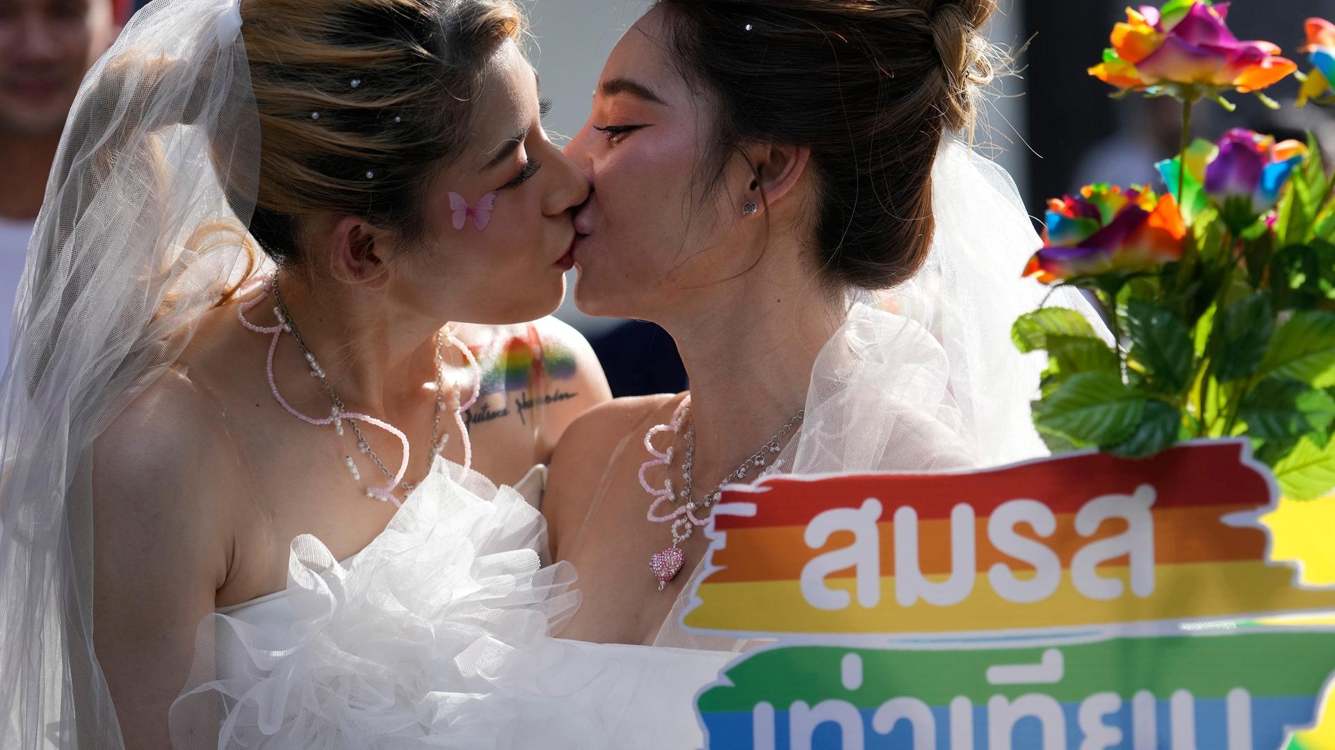 Bangkok: Zwei Frauen küssen sich während einer Pride-Parade in Bangkok, Thailand, während sie ein Plakat zur Unterstützung der Ehegleichheit halten.
