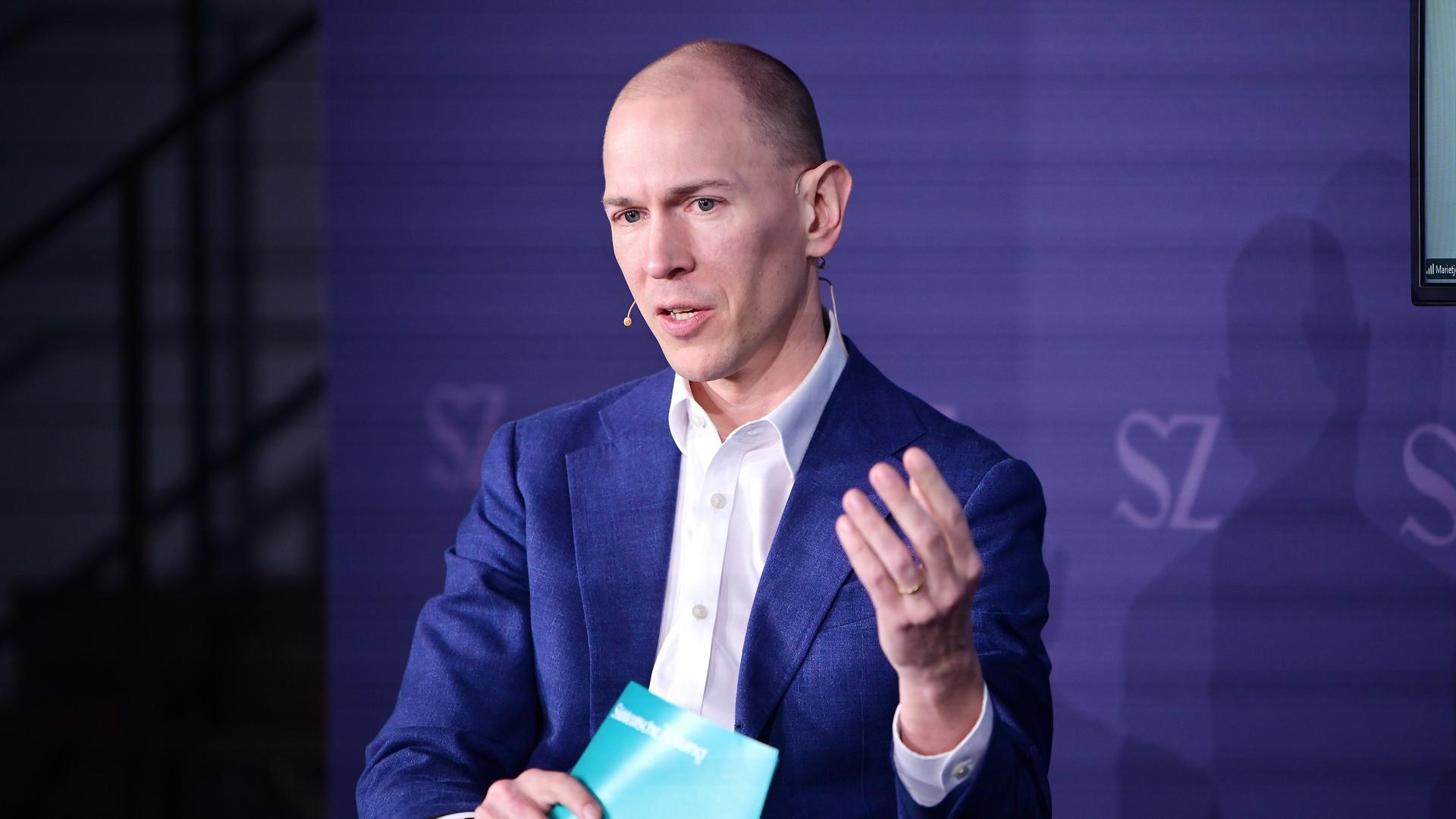 Jannis Brühl sitzt beim Digitalgipfel der "Süddeutschen Zeitung" auf dem Podium und gestikuliert beim Sprechen. Jannis Brühl sitzt beim Digitalgipfel der "Süddeutschen Zeitung" auf dem Podium und gestikuliert beim Sprechen.