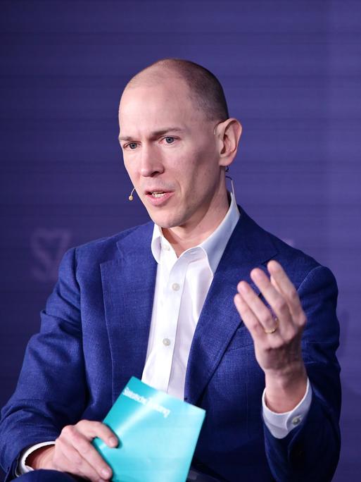 Jannis Brühl sitzt beim Digitalgipfel der "Süddeutschen Zeitung" auf dem Podium und gestikuliert beim Sprechen. Jannis Brühl sitzt beim Digitalgipfel der "Süddeutschen Zeitung" auf dem Podium und gestikuliert beim Sprechen.