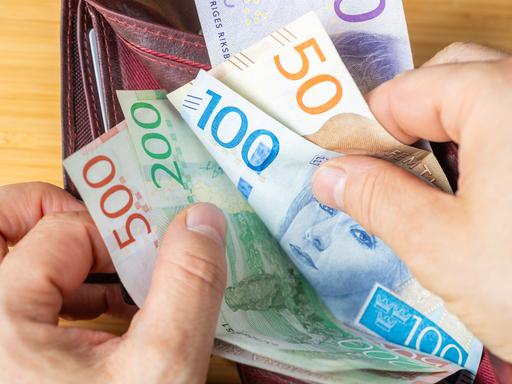Eine Person durchblättert ihr Portemonnaie mit schwedischen Kronen Geldscheinen. Eine Person durchblättert ihr Portemonnaie mit schwedischen Kronen Geldscheinen.