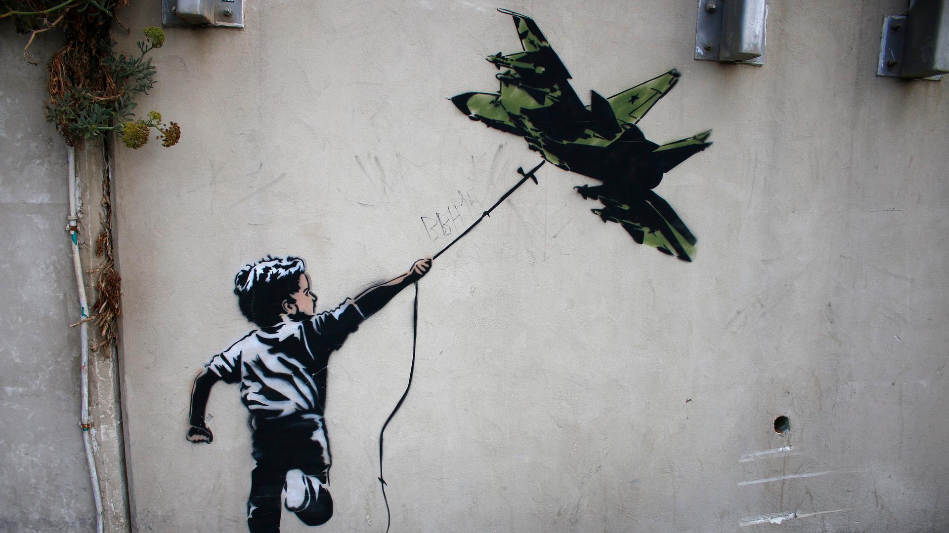 Street Art in Tel Aviv: Ein Banksy zugeschriebenes Graffiti zeigt einen Jungen, der ein Kampflugzeug wie einen Drachen fliegen lässt.