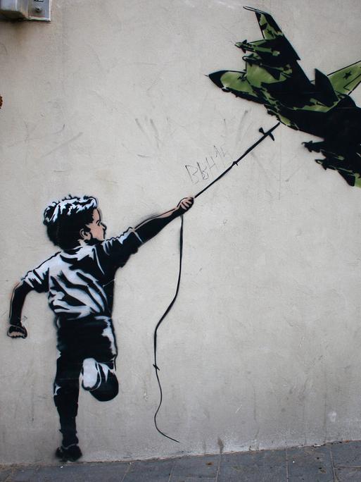 Street Art in Tel Aviv: Ein Banksy zugeschriebenes Graffiti zeigt einen Jungen, der ein Kampflugzeug wie einen Drachen fliegen lässt.