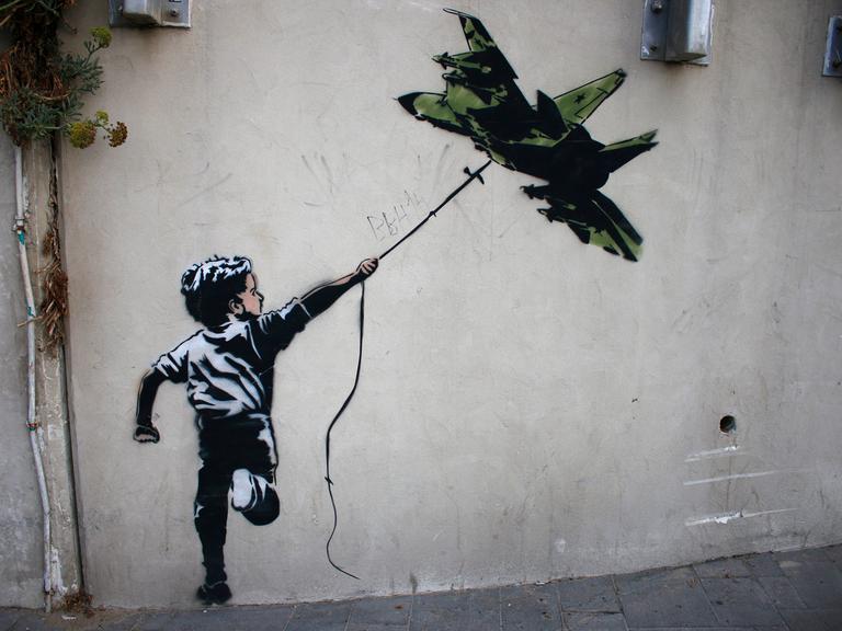 Street Art in Tel Aviv: Ein Banksy zugeschriebenes Graffiti zeigt einen Jungen, der ein Kampflugzeug wie einen Drachen fliegen lässt.