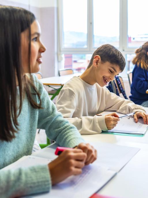 Grundschüler, die während des Unterrichts in ihre Hefte schreiben, Lern- und Bildungskonzept 