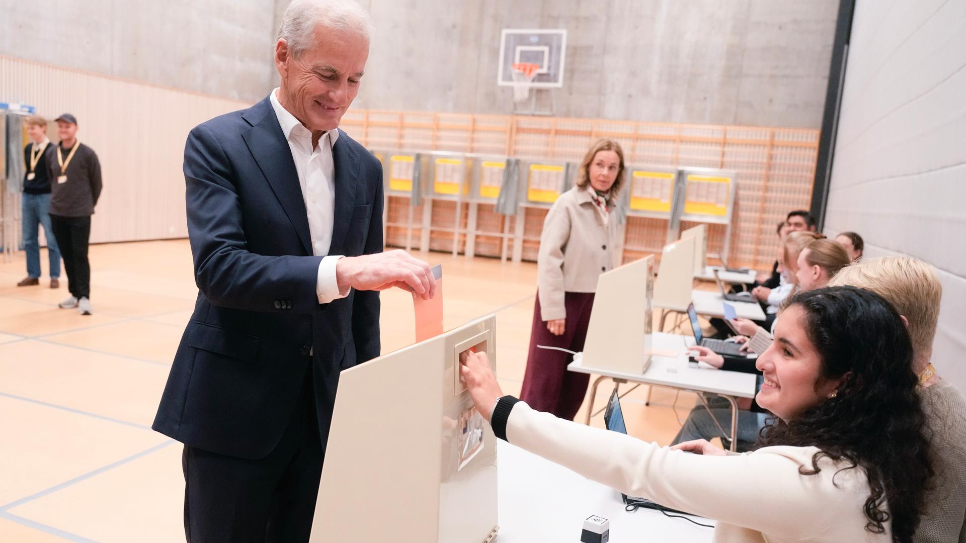 Ein Mann steckt seinen Stimmzettel in eine Wahlurne.