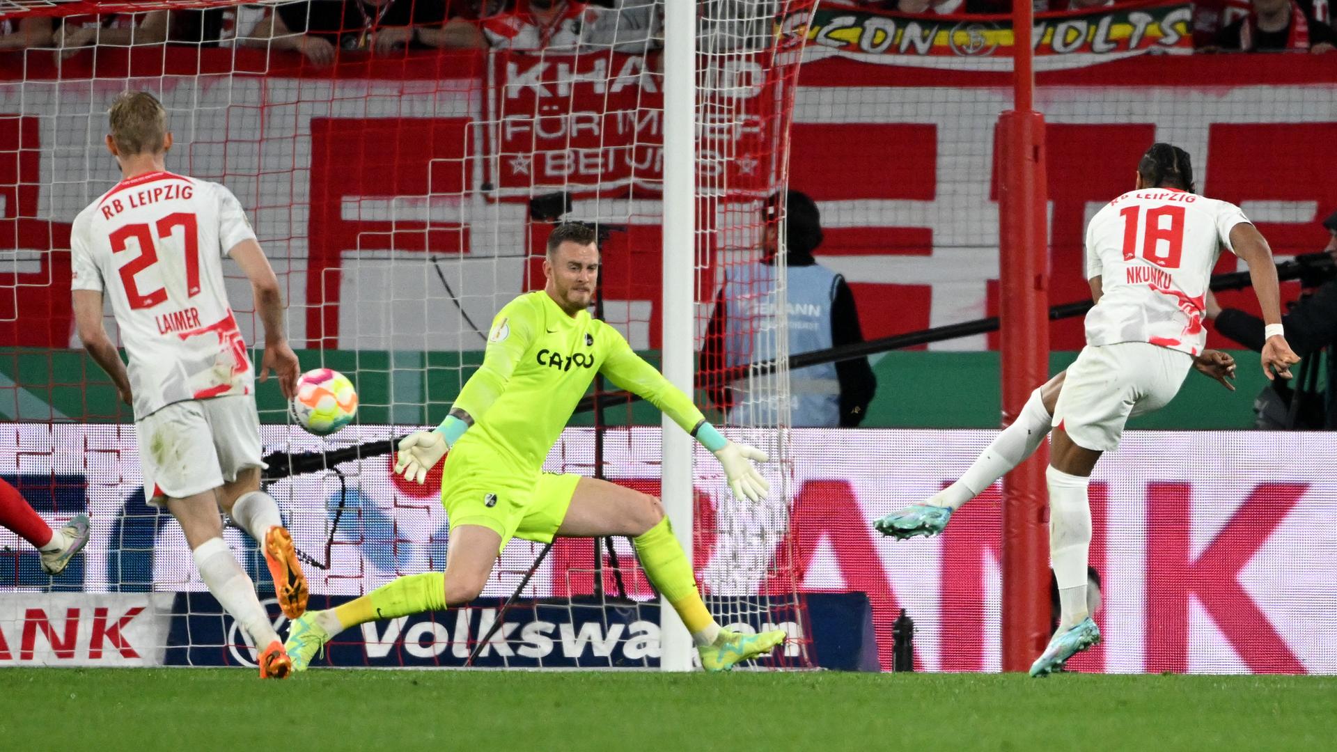 Halbfinale im DFB-Pokal: SC Freiburg gegen RB Leipzig. Leipzigs Christopher Nkunku (r) erzielt gegen Freiburgs Torwart Mark Flekken das Tor zum 4:0. Halbfinale im DFB-Pokal: SC Freiburg gegen RB Leipzig. Leipzigs Christopher Nkunku (r) erzielt gegen Freiburgs Torwart Mark Flekken das Tor zum 4:0.