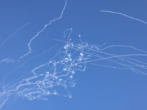 Das israelische Abwehrsystem schießt aus dem Libanon abgefeuerte Raketen ab. Die Rauchspuren sind am blauen Himmel zu sehen.