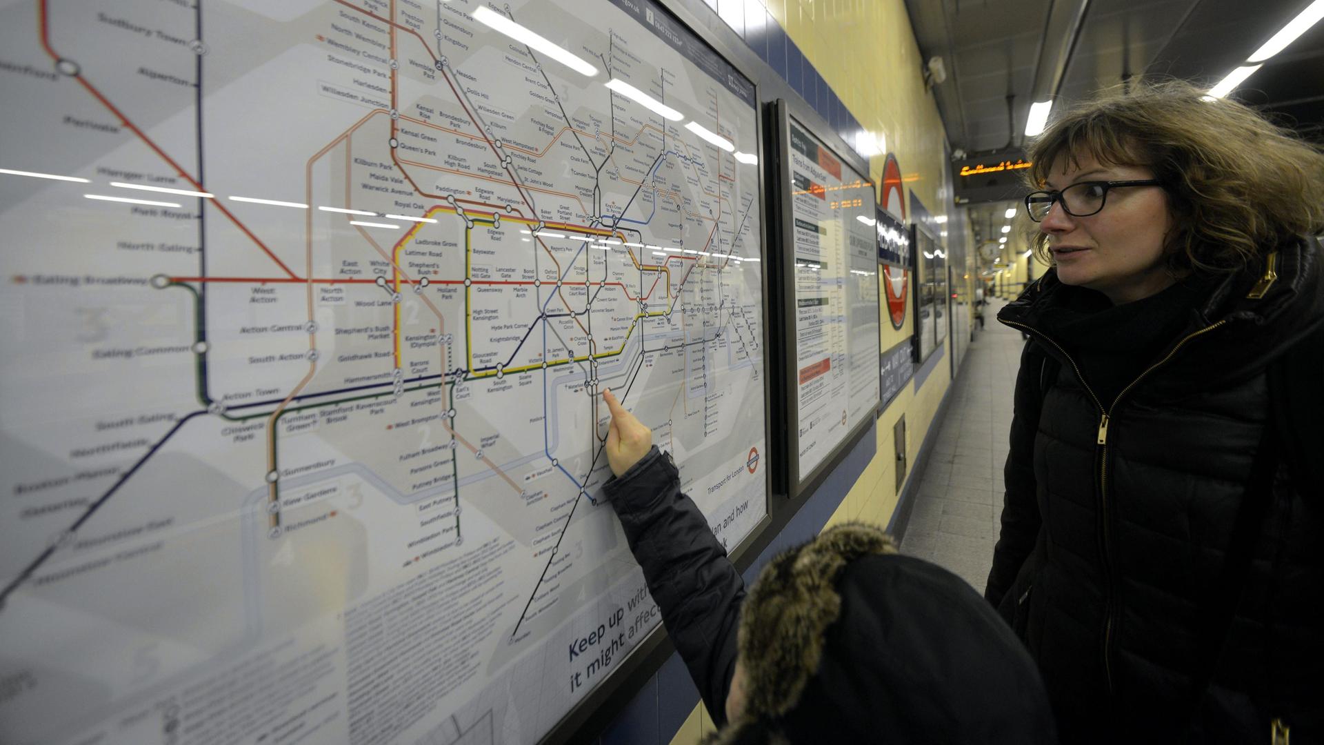 Eine Frau und ein Kind schauen gemeinsam auf einen Netzplan der Londoner U-Bahn. 