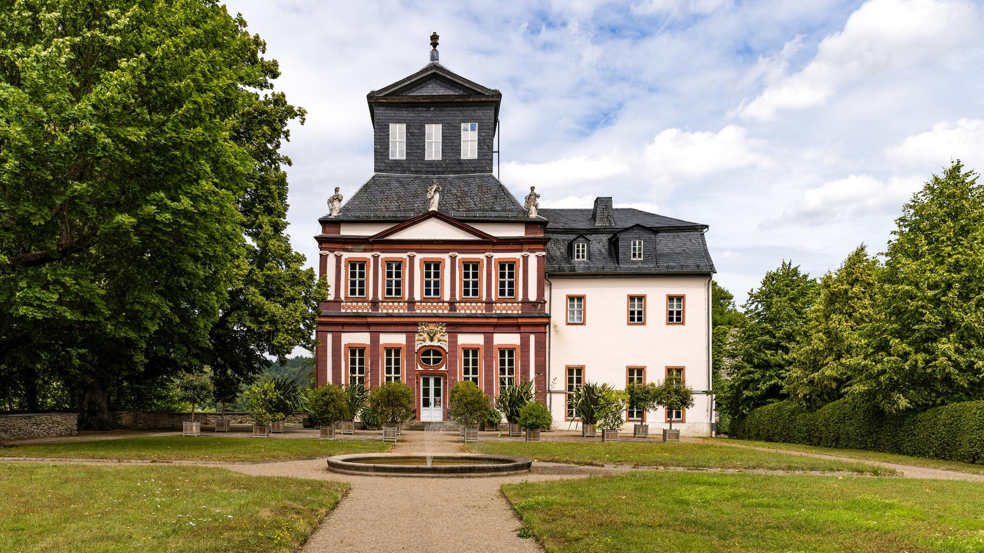 Hinter einem Springbrunnen steht das Schloss Schwarzburg in einem Park. Hinter einem Springbrunnen steht das Schloss Schwarzburg in einem Park.