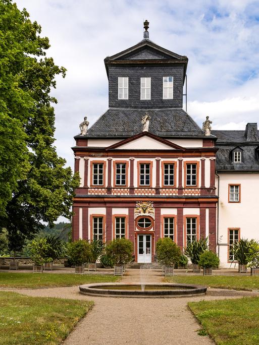 Hinter einem Springbrunnen steht das Schloss Schwarzburg in einem Park.