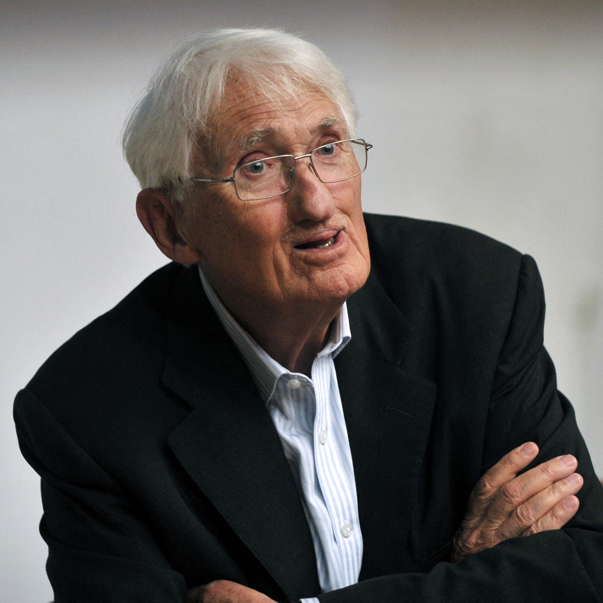 Porträt von Jürgen Habermas. Er hat weißes Haar und trägt ein schwarzes Sakko über einem blau gestreiften Hemd.