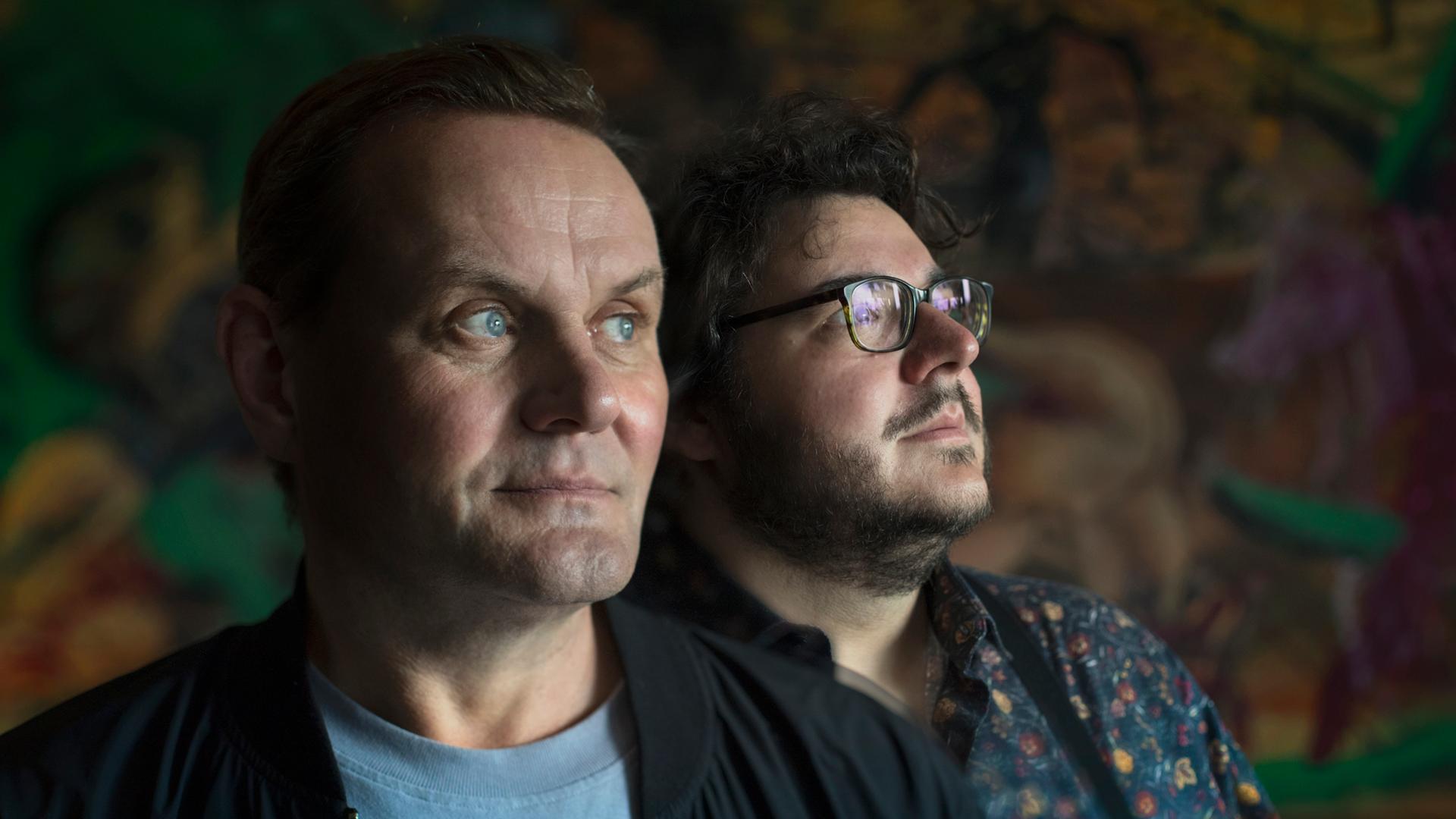 Devid Striesow und Axel Ranisch stehen in einem dunklen Raum und schauen zur Seite. Devid Striesow und Axel Ranisch stehen in einem dunklen Raum und schauen zur Seite.