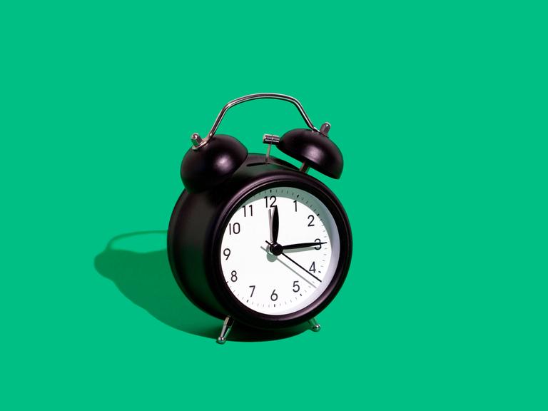 Ein schwarzer Wecker vor einem grünen Hintergrund