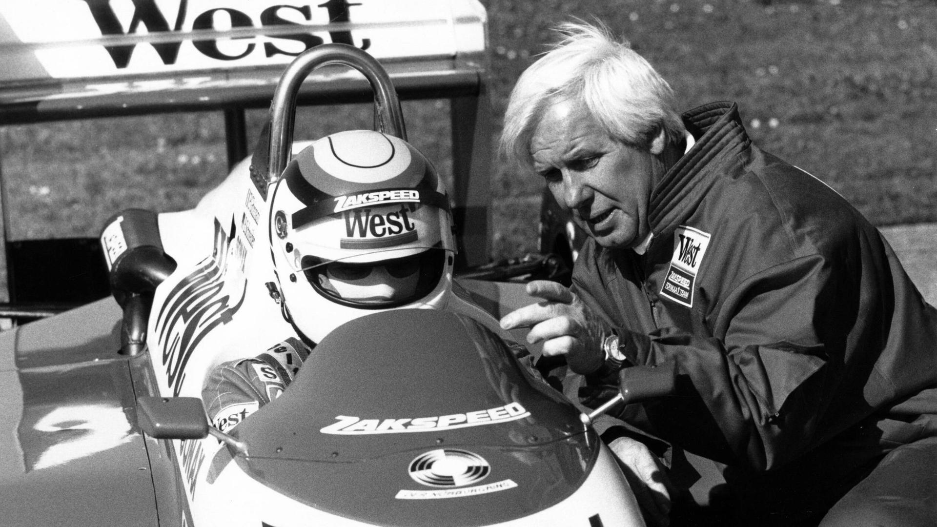 Der damalige Zakspeed-Teamchef Erich Zakowski im Jahr 1988. Er spricht mit Bernd Schneider, dem Fahrer, der in einem Rennwagen von Zakspeed sitzt. Der damalige Zakspeed-Teamchef Erich Zakowski im Jahr 1988. Er spricht mit Bernd Schneider, dem Fahrer, der in einem Rennwagen von Zakspeed sitzt.
