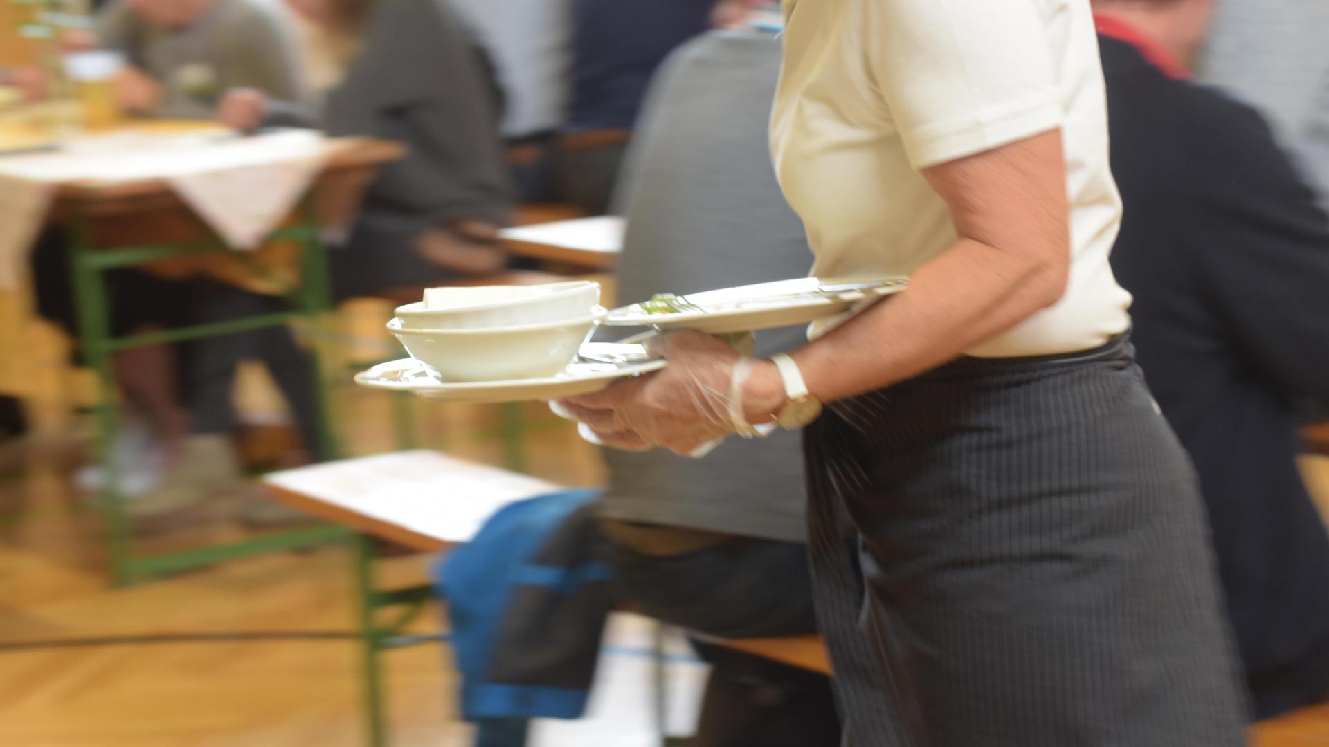 Eine Kellnerin räumt Geschirr ab.