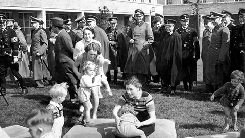 Ehrengäste des Führers auf dem Reichssportfeld sehen zu, wie Frauen mit Kleinkindern spielen. Im Hintergrund Offiziere der Wehrmacht, der Allgemeinen SS, des Auswärtigen Amts und einer ausländischen Delegation.