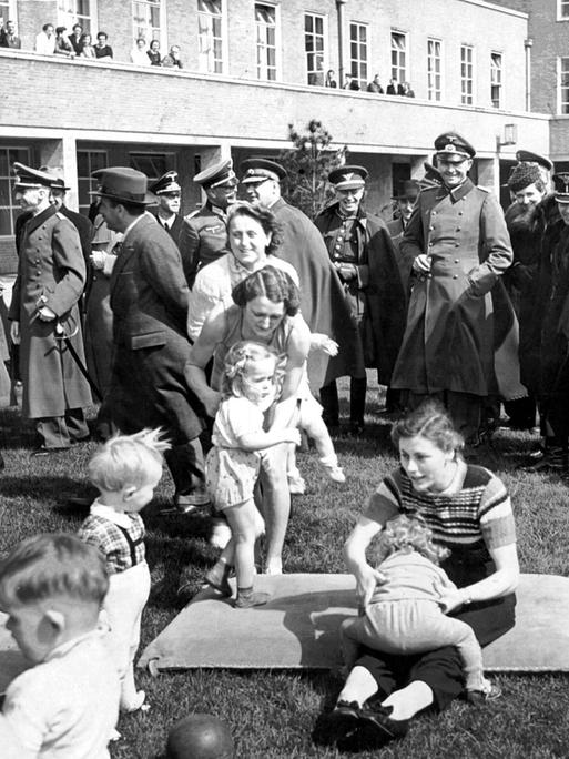 Ehrengäste des Führers auf dem Reichssportfeld sehen zu, wie Frauen mit Kleinkindern spielen. Im Hintergrund Offiziere der Wehrmacht, der Allgemeinen SS, des Auswärtigen Amts und einer ausländischen Delegation.