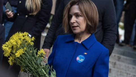 Maia Sandu, Präsidentin der Republik Moldau, trägt zur Stimmabgabe bei den moldauischen Parlamentswahlen einen blauen Blazer und hat gelbe Blumen in der Hand.