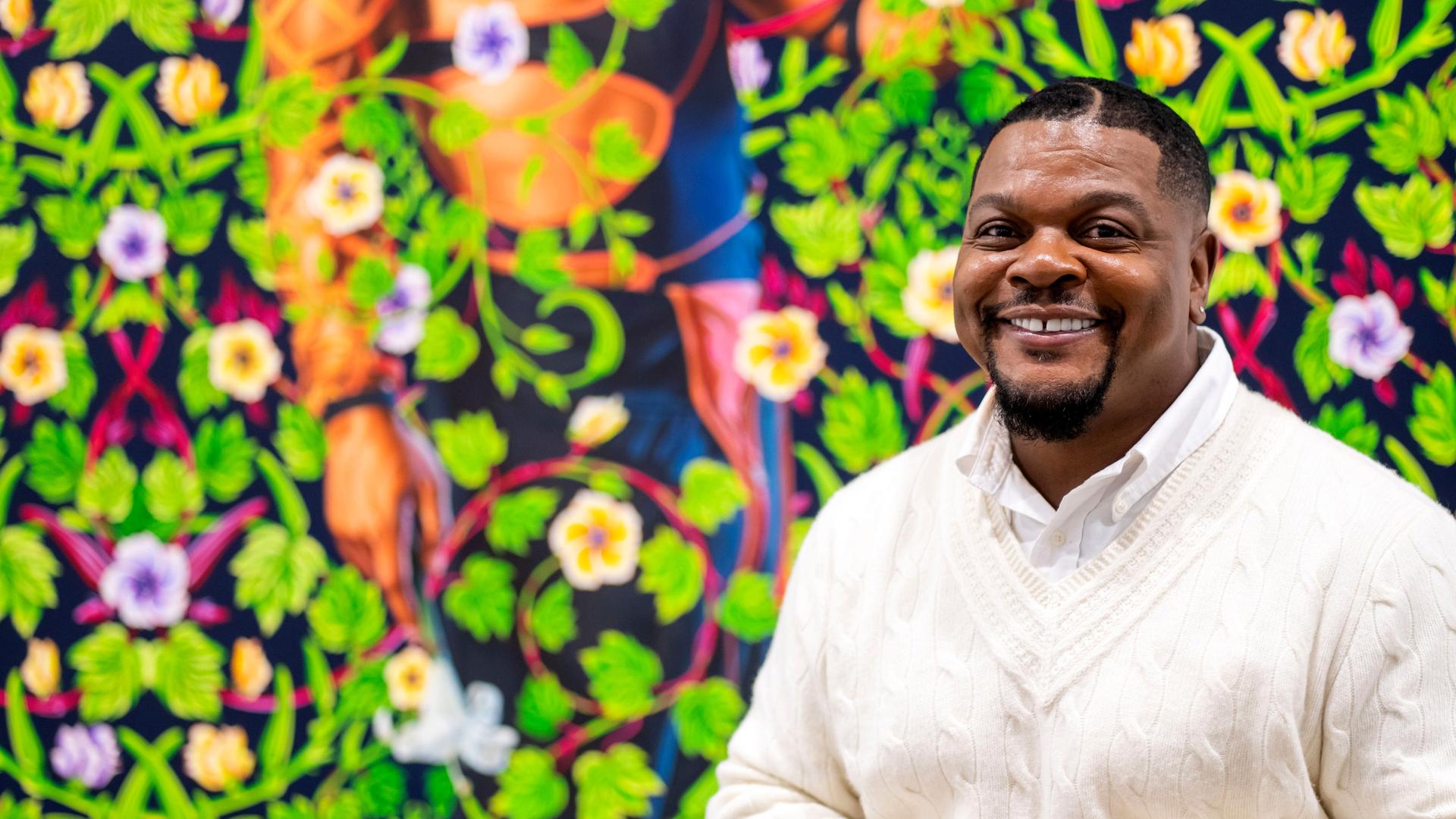 Kehinde Wiley vor einem einer Bilder mit grünen Blätterranken und Blüten Kehinde Wiley vor einem einer Bilder mit grünen Blätterranken und Blüten