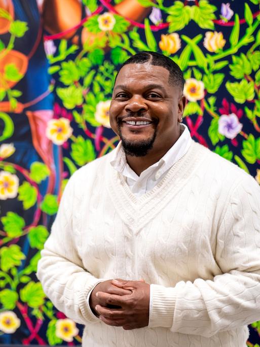 Kehinde Wiley vor einem einer Bilder mit grünen Blätterranken und Blüten Kehinde Wiley vor einem einer Bilder mit grünen Blätterranken und Blüten