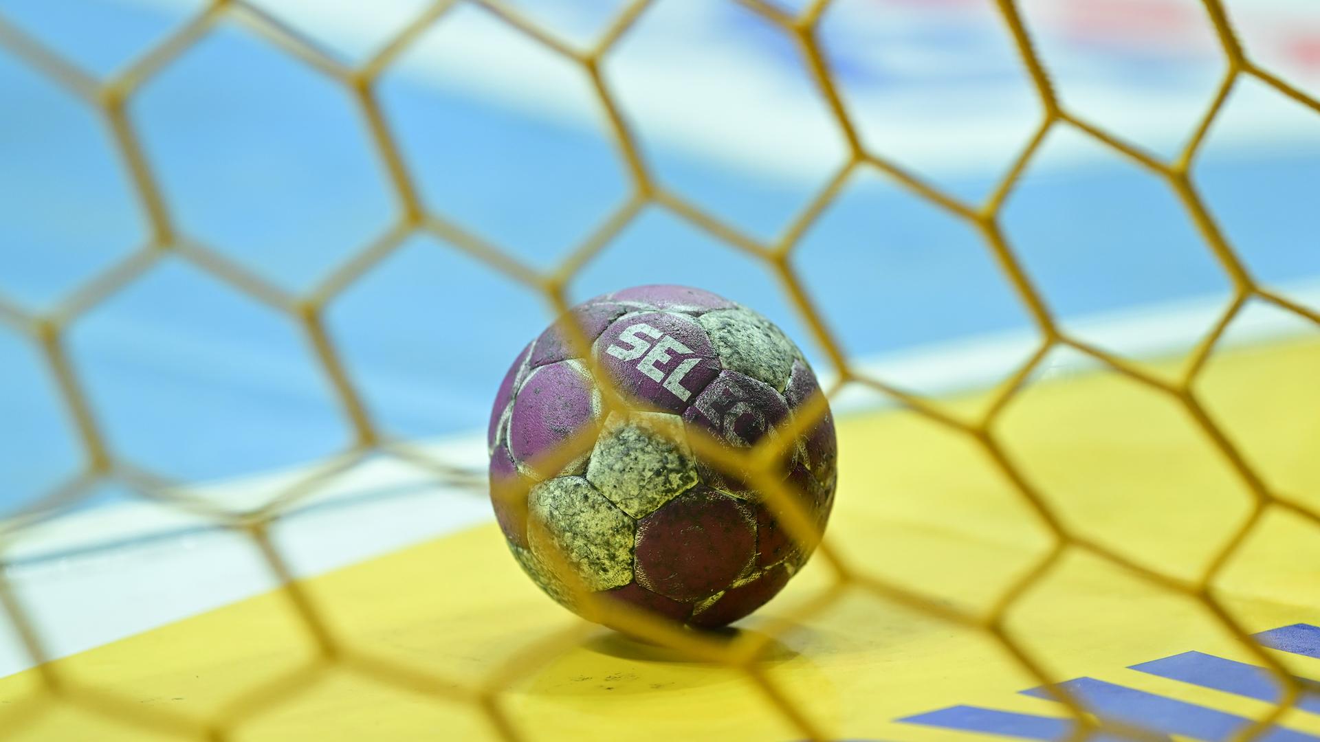 Ein Handball liegt auf dem Hallenboden, Blick durchs Tornetz