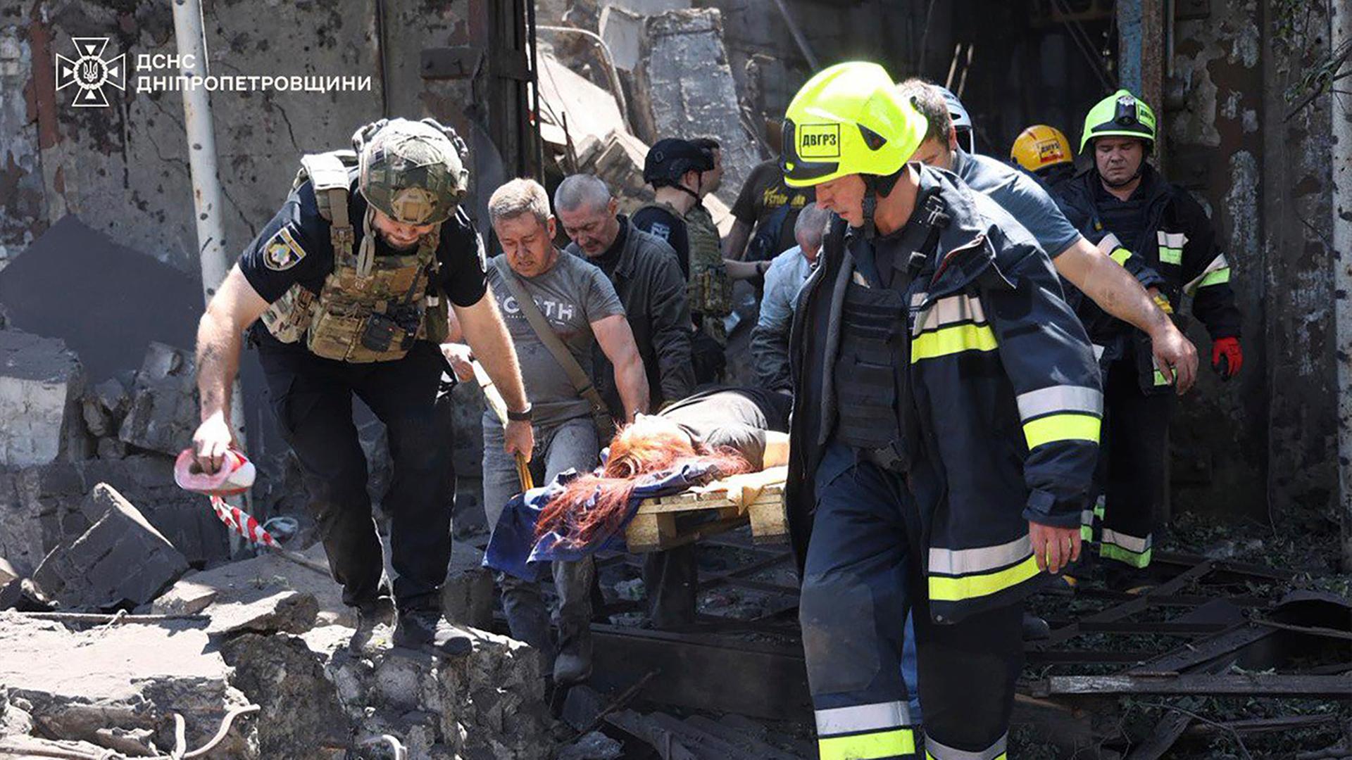 Auf diesem vom ukrainischen Rettungsdienst zur Verfügung gestellten Foto tragen Rettungskräfte eine verletzte Person nach dem russischen Raketenangriff in Dnipro. Auf diesem vom ukrainischen Rettungsdienst zur Verfügung gestellten Foto tragen Rettungskräfte eine verletzte Person nach dem russischen Raketenangriff in Dnipro.