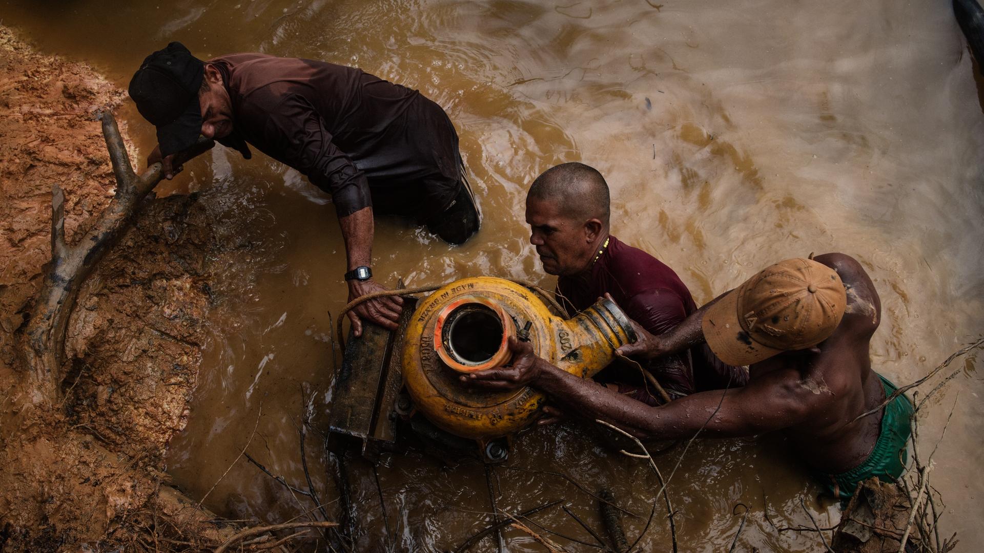 Illegale Goldwäscher bergen eine Maschine, die sie zuvor bei einer Polizeirazzia ins Wasser geworfen haben, um sie zu verstecken.