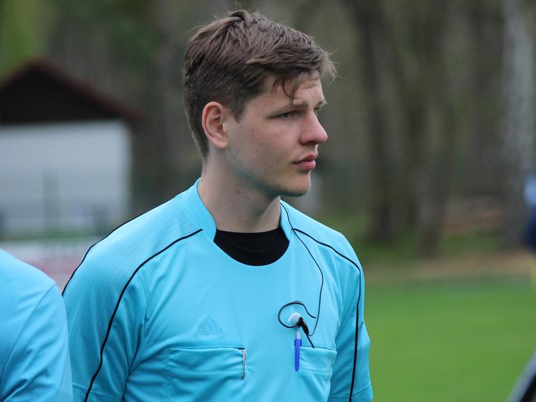 Marius, ein junger Mann, in Schiedsrichter-Trikot