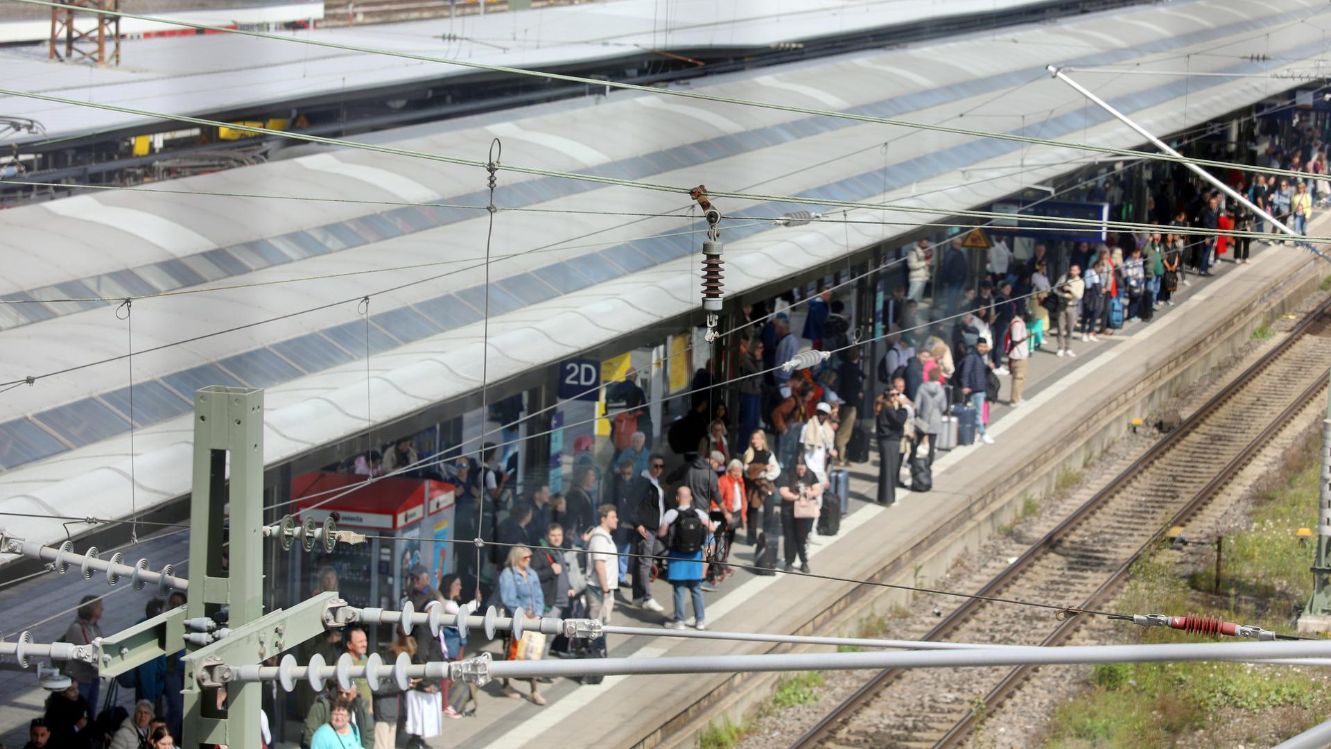 Baden-Württemberg, Ulm: Viele Reisende stehen an einem Bahngleis im Hauptbahnhof.