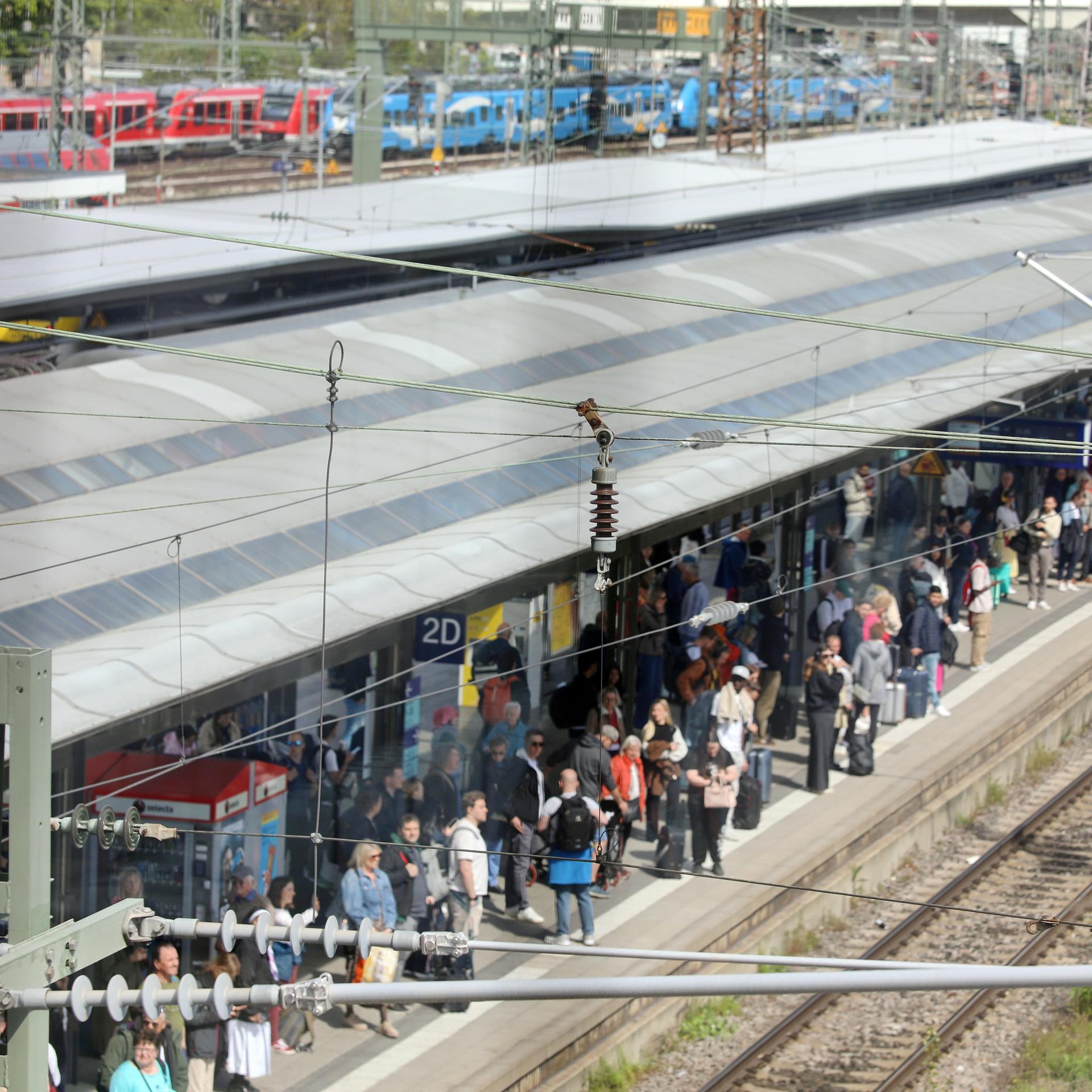 Baden-Württemberg, Ulm: Viele Reisende stehen an einem Bahngleis im Hauptbahnhof.