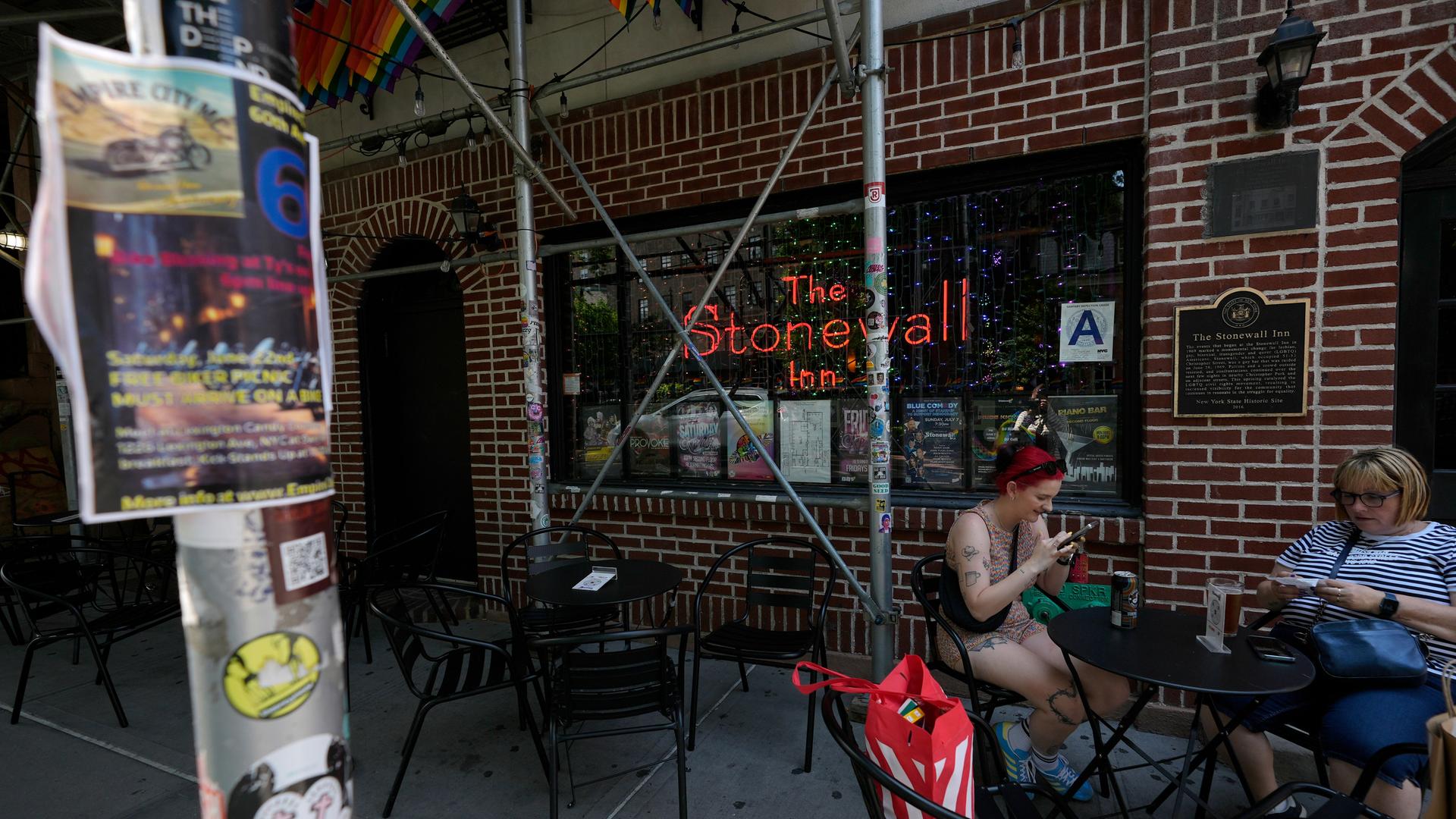 Menschen sitzen vor dem Stonewall Inn, in New York, neben dem nun ein Besucherzentrum zur Geschichte der Rebellion von 1969 im Stonewall Inn informmiert. Menschen sitzen vor dem Stonewall Inn, in New York, neben dem nun ein Besucherzentrum zur Geschichte der Rebellion von 1969 im Stonewall Inn informmiert.
