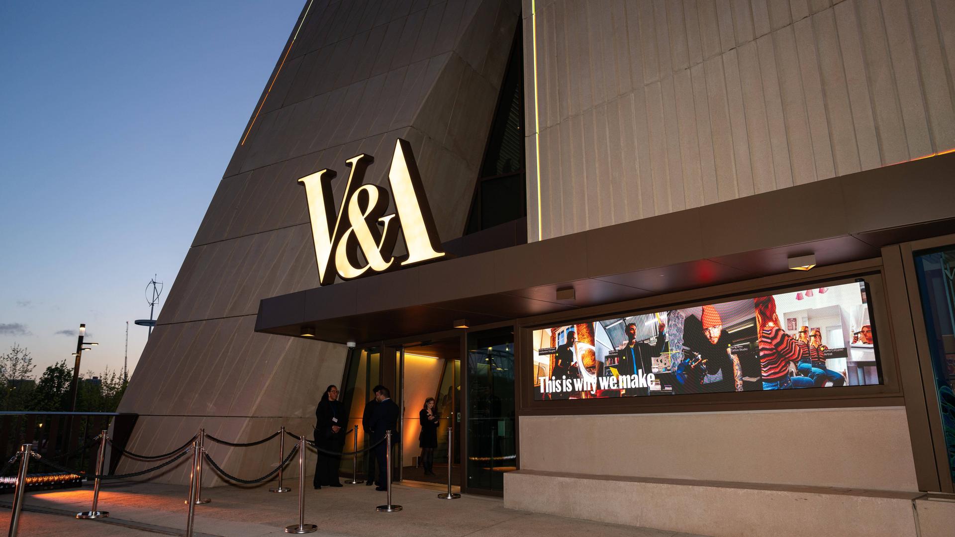 Das neue V&A East Museum in London. Es besteht aus viel Beton, über dem Eingang hängen in Gold die Buchstaben V&A.