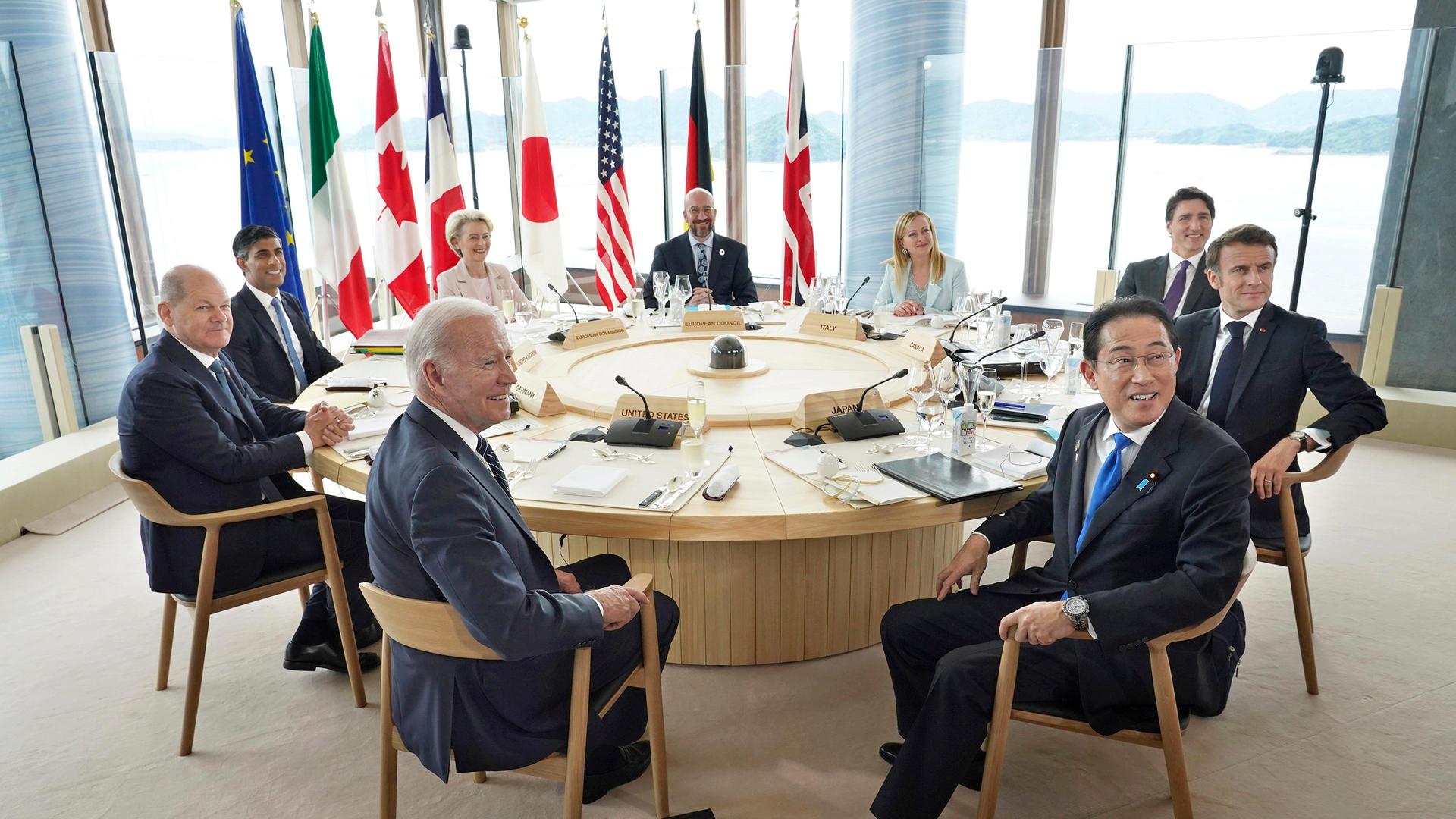 Die Staats- und Regierungschefs der G7-Staaten sitzen um einen runden Tisch. Hinter ihnen die Landesfahnen.