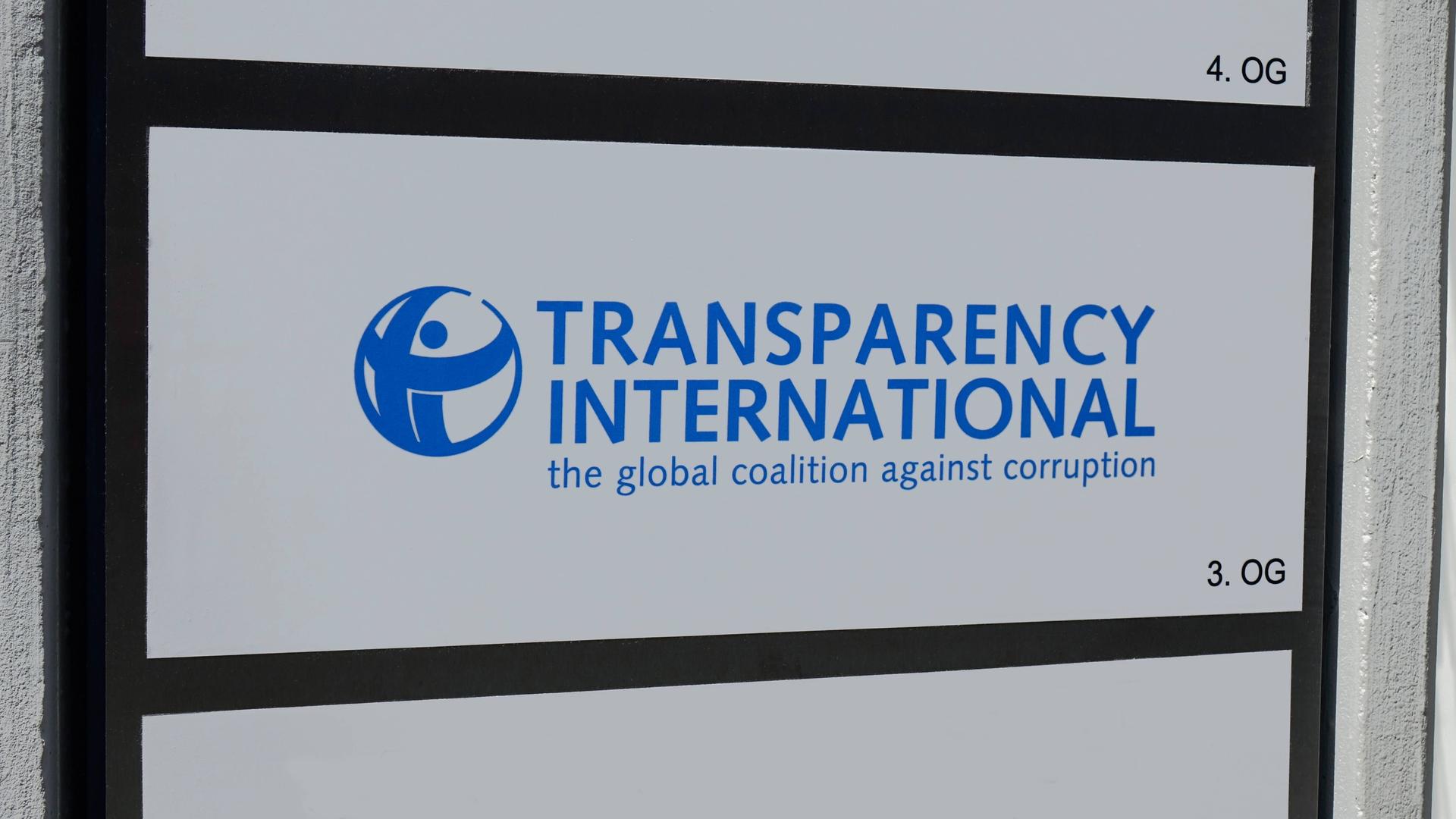Auf einem Schild befindet sich das Logo und der Schriftzug von Transparency International. Auf einem Schild befindet sich das Logo und der Schriftzug von Transparency International.