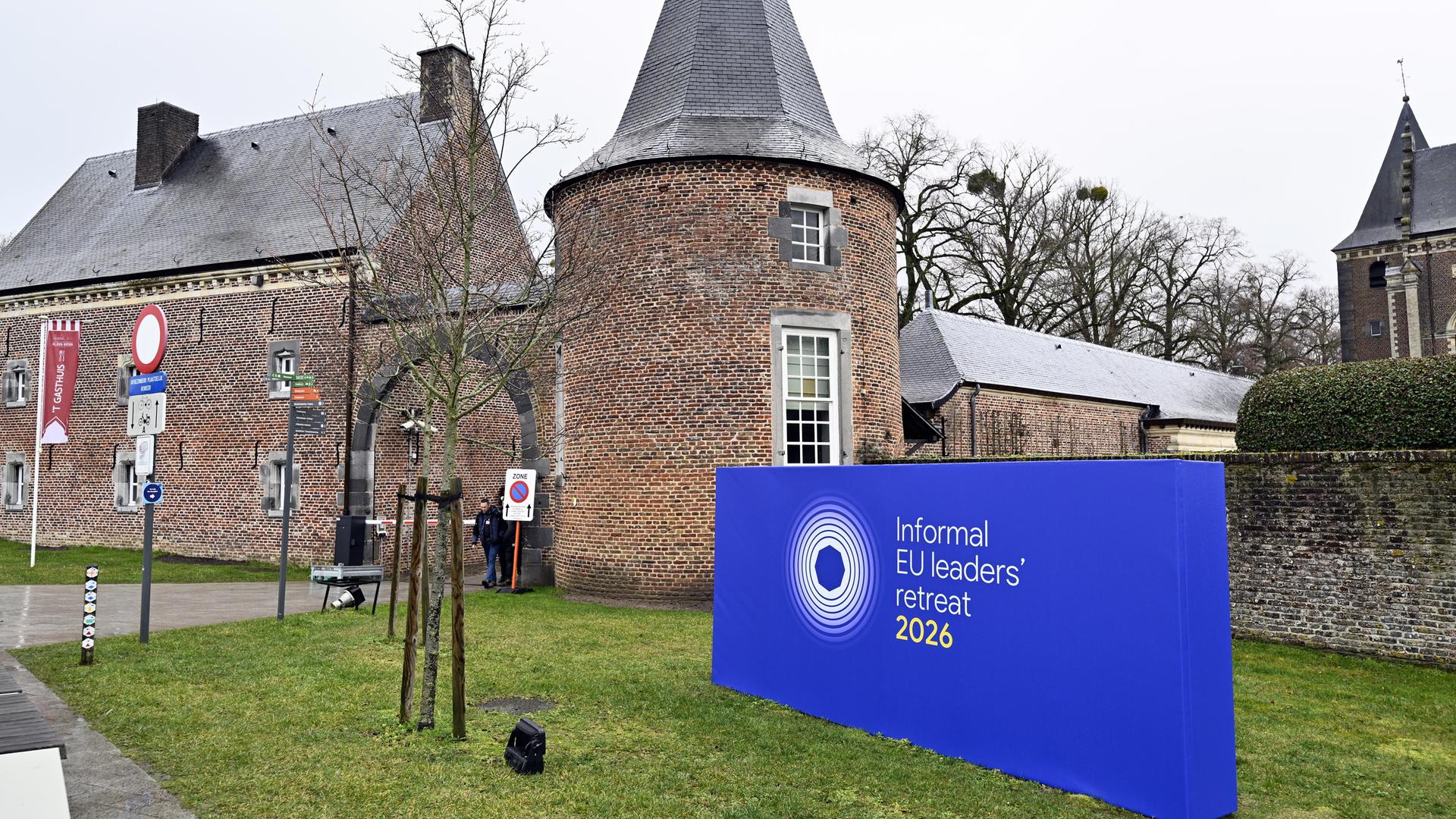 Einfahrt zu Schloss Alden Biesen. Im Vordergrund eine blaue Tafel mit der Aufschrift "Informal EU leader's retreat 2026"