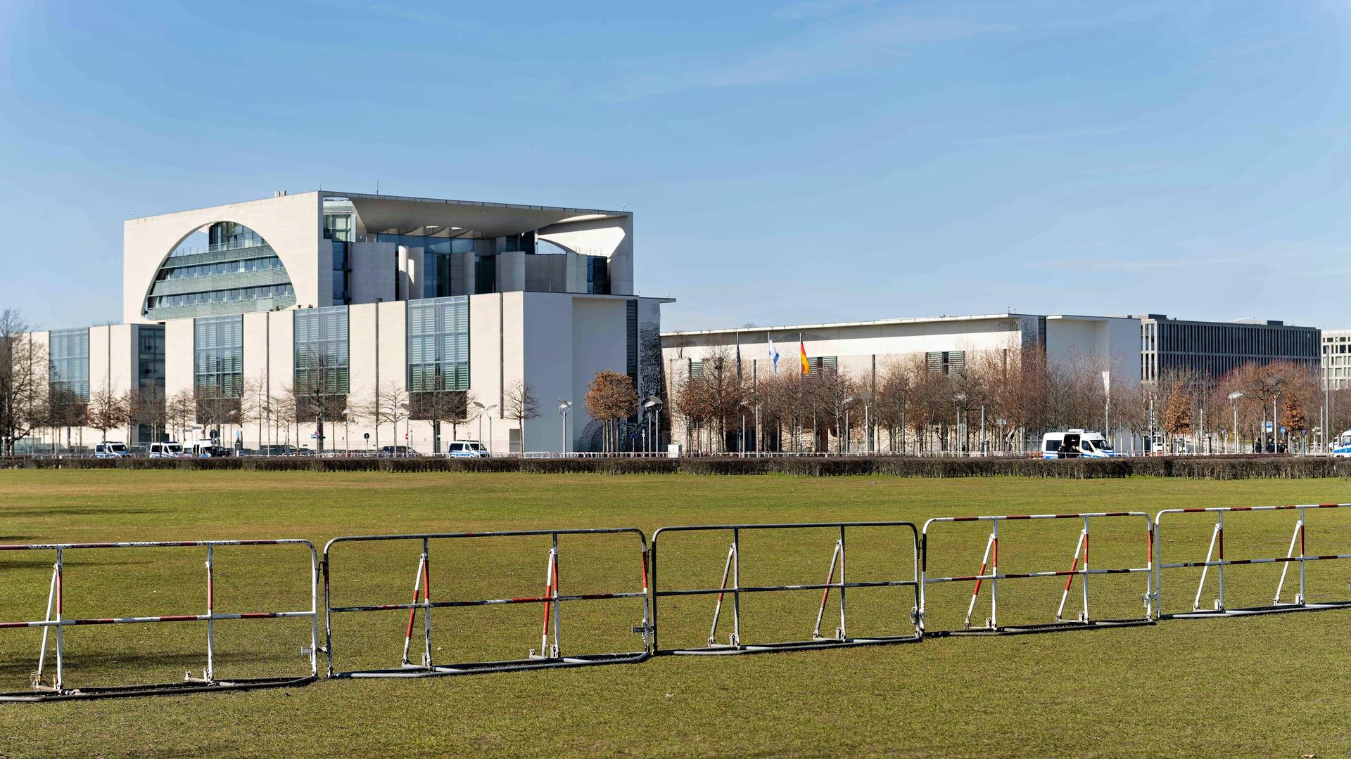 Auf einer Wiese vor dem Bundeskanzleramt stehen Absperrgitter.