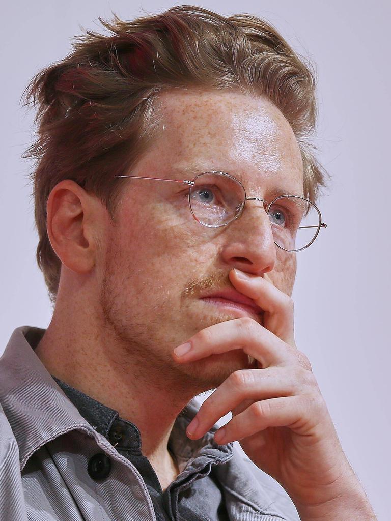 Porträt von Leon Engler mit Hemd und Brille. Seine linke Hand hält er nachdenklich vor dem Mund. Sein Blick ist konzentriert.