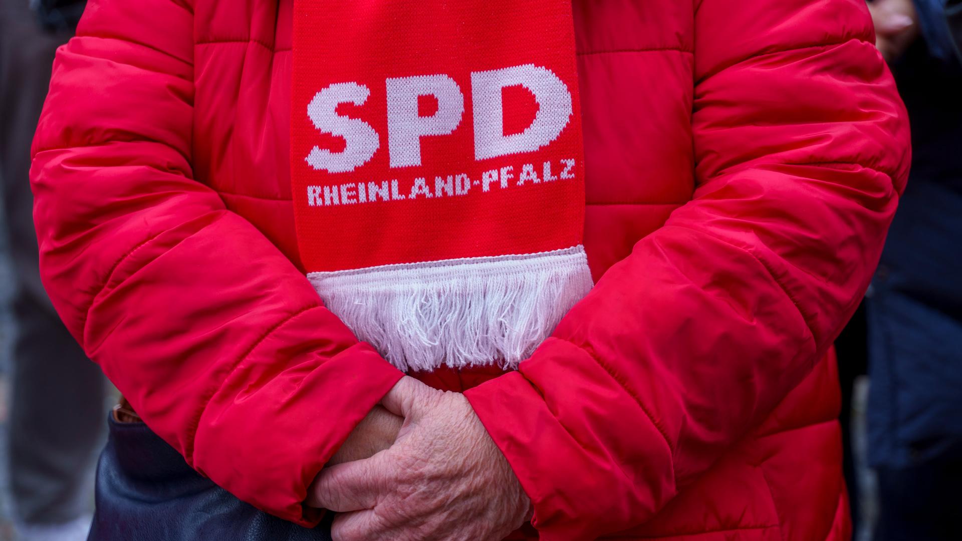 Eine ältere SPD-Anhängerin ist komplett in „Rot“ gekleidet. Sie trägt eine rote Winterjacke und einen Schal mit der Aufschrift "SPD Rheinland-Pfalz".